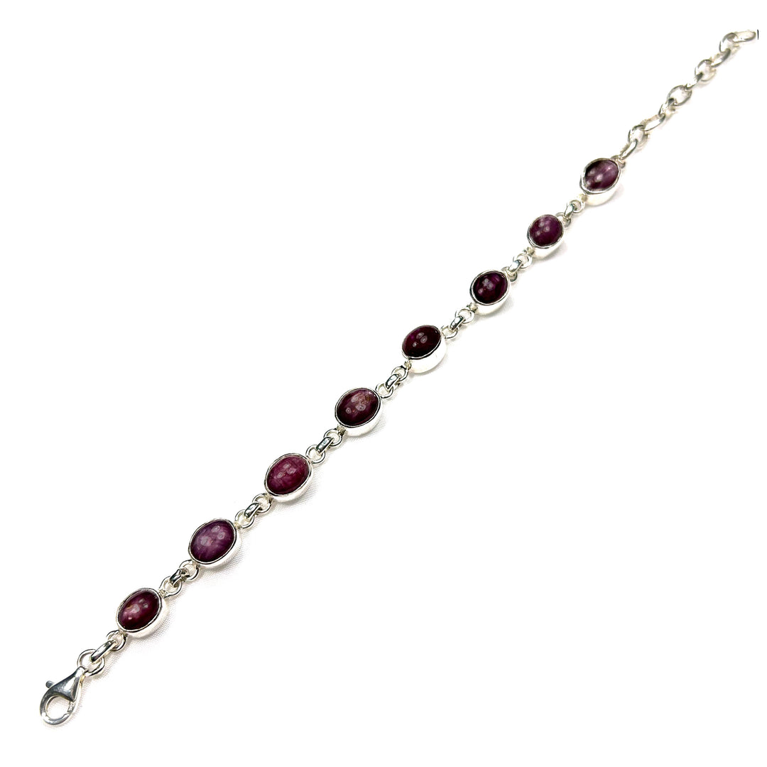 Silver bracelet with red gemstones on a white background