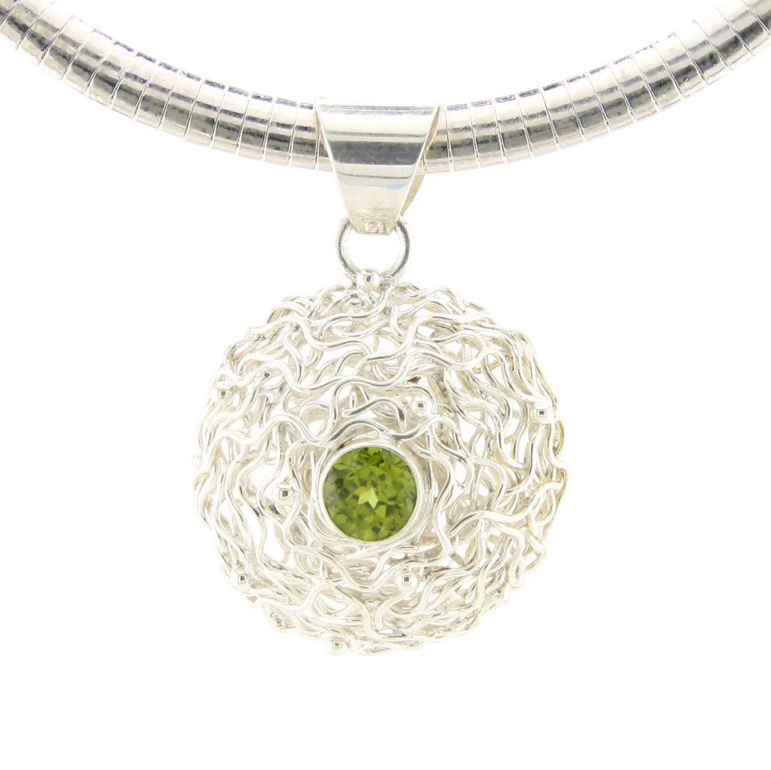 Silver necklace with a round pendant featuring a green gemstone on a white background