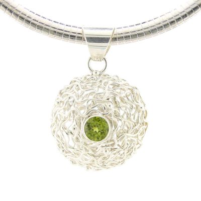 Silver necklace with a round pendant featuring a green gemstone on a white background